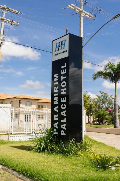 a sign in the grass in front of a house at Paramirim Palace Hotel in Paramirim