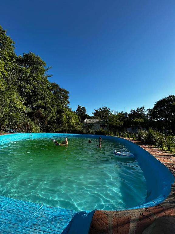 a swimming pool with people in the water at El Paso Ibera Cabañas in Colonia Carlos Pellegrini