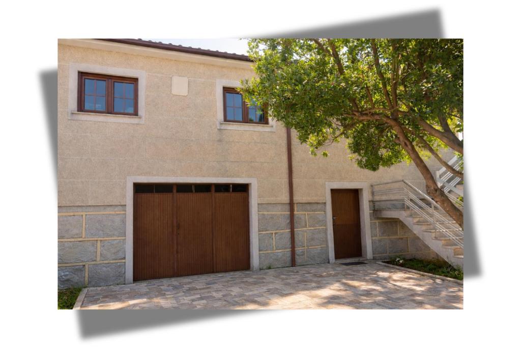 a house with two garage doors and a tree at Casa das Quintas com vista para a montanha in Boticas