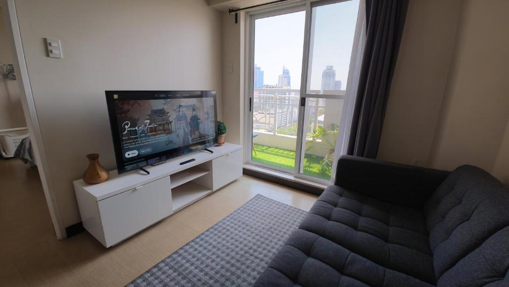 a living room with a tv and a couch and a window at Manila Sunset View in Manila