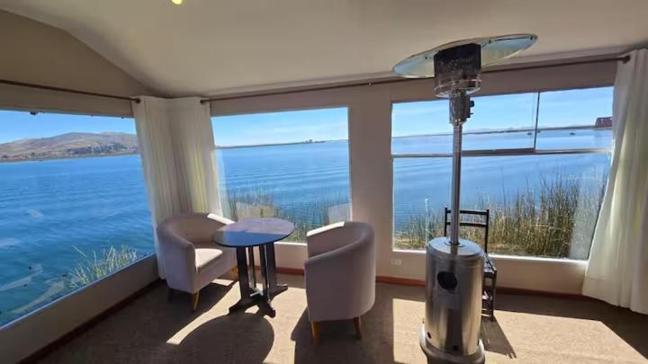 a room with a large window with a view of the ocean at Uros Sunset Lodge in Puno