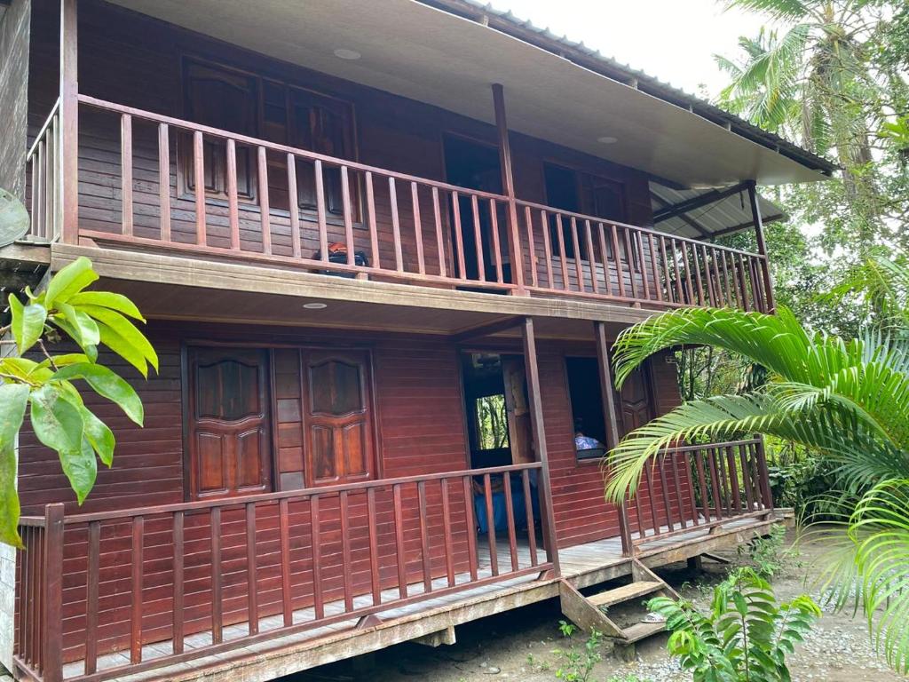 a wooden house with a porch and a balcony at Posada el arrecife in Nuquí