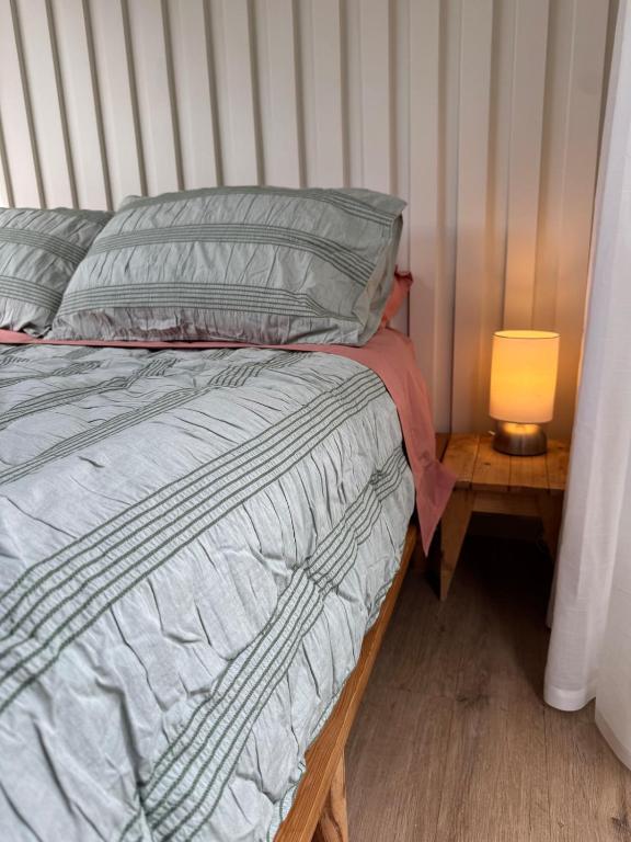 a bed in a room with a lamp on a table at Tiny Escape in Lennox Head