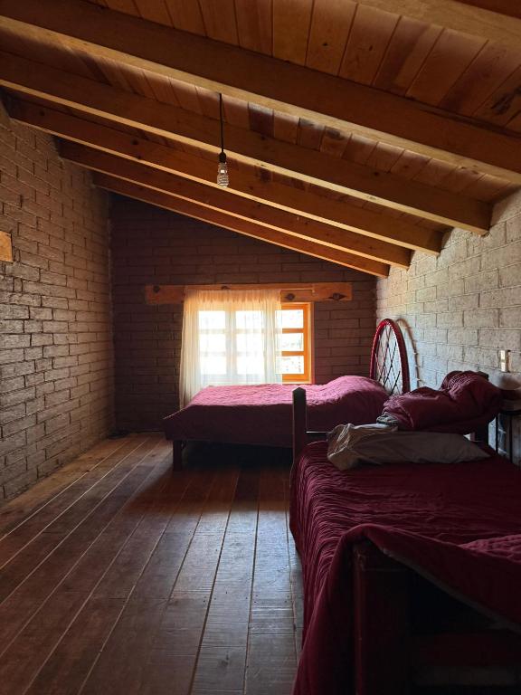 a attic room with two beds and a window at Cabaña Cuevas Tapalpa in Tapalpa