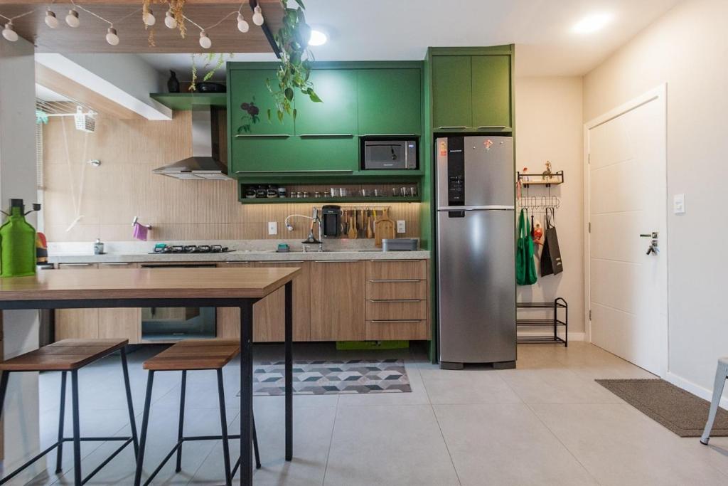 a kitchen with green cabinets and a wooden table at Moderno & Prático Centro in Florianópolis
