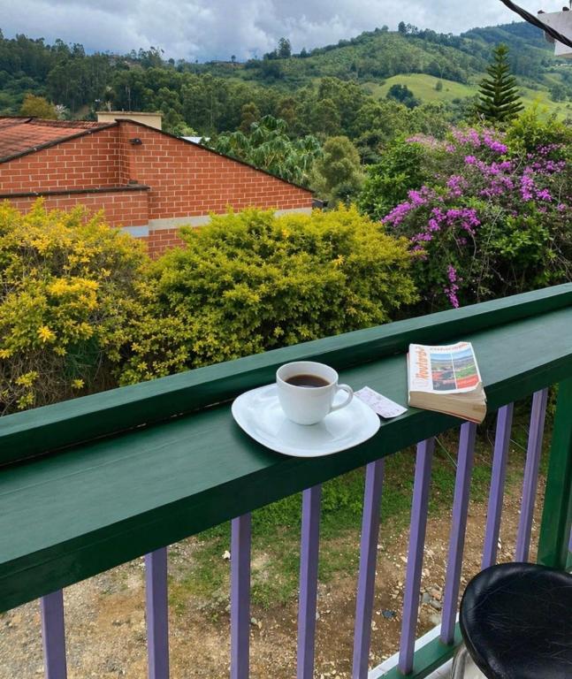 a cup of coffee and a book on a balcony at Casita entera en Salento para 10 personas cerca a la plaza in Salento