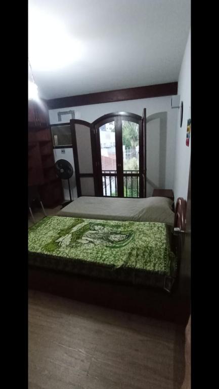 a bedroom with a bed with a green comforter and a window at Casa Quarto 3 in Jaraguá do Sul