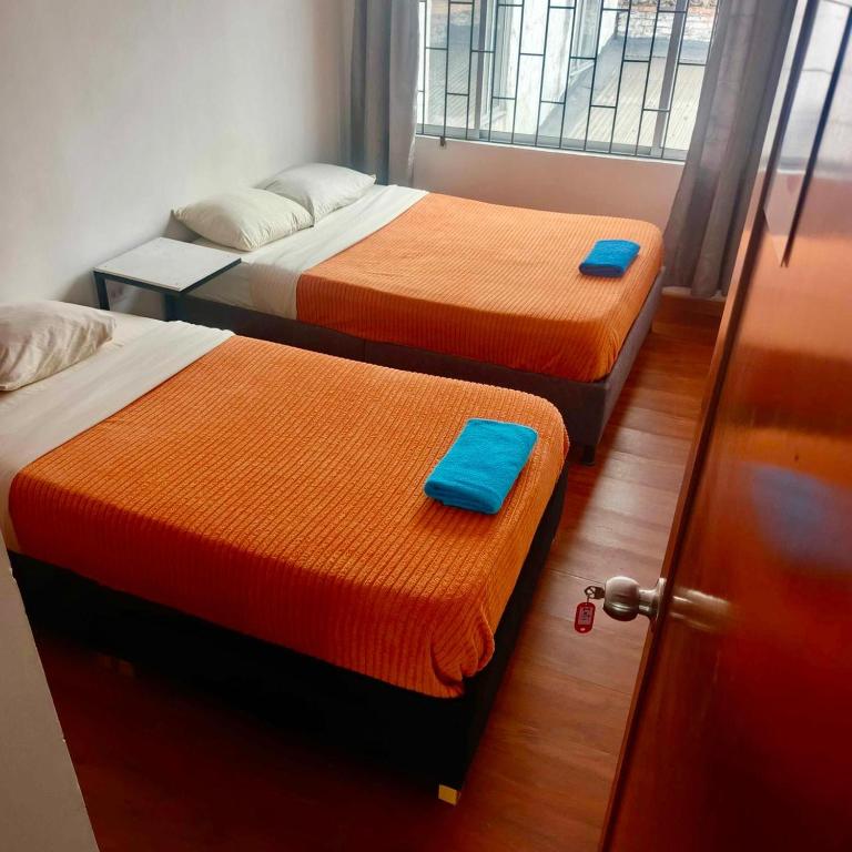a room with two beds and a door with a door at Yachi Hostel et Kuyay in Bogotá