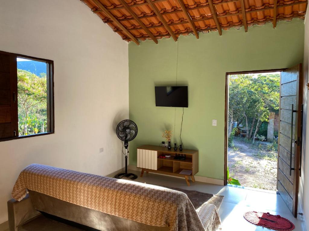a bedroom with a bed and a flat screen tv at Casa Lilás no Vale do Capão in Vale do Capao
