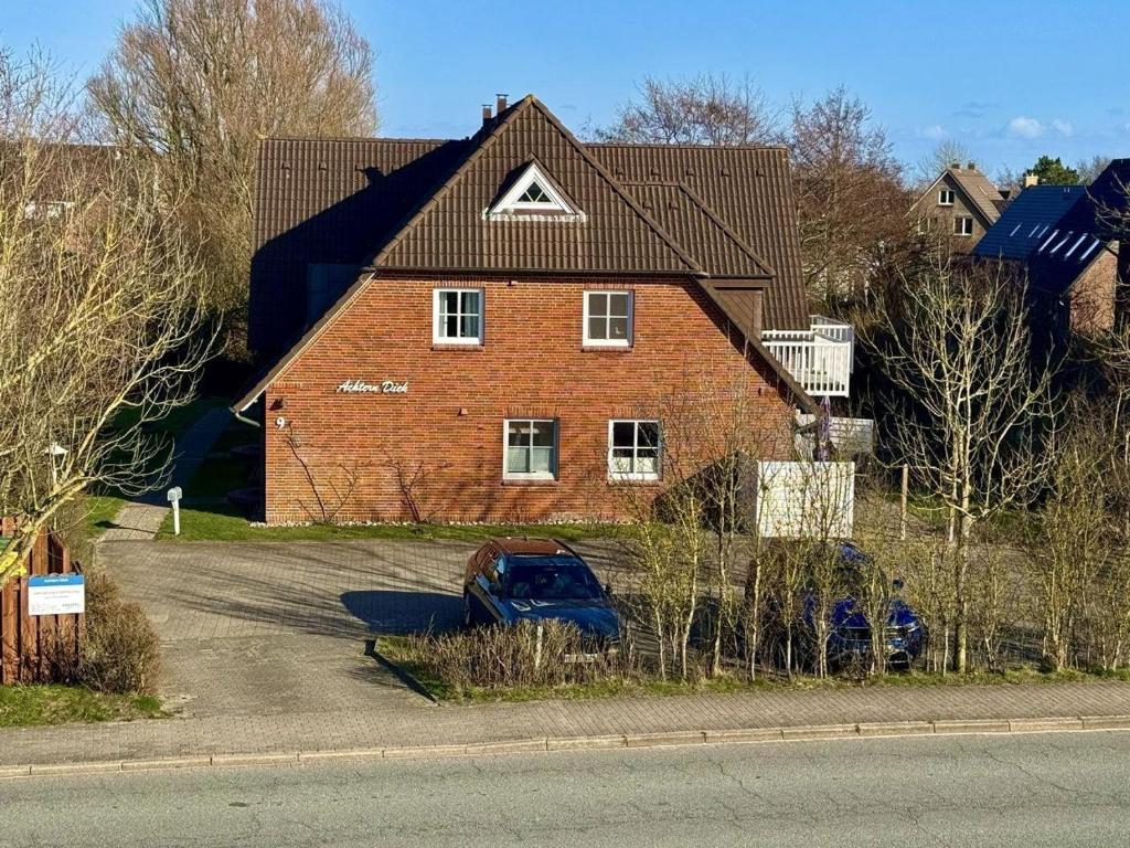 a red brick house with a car parked in the driveway at Achtern-Diek-1 in Brösum