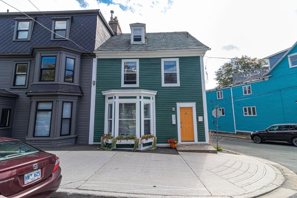 a green house with a orange door on a street at The Bannerman Park Suite and Loft in St. John's