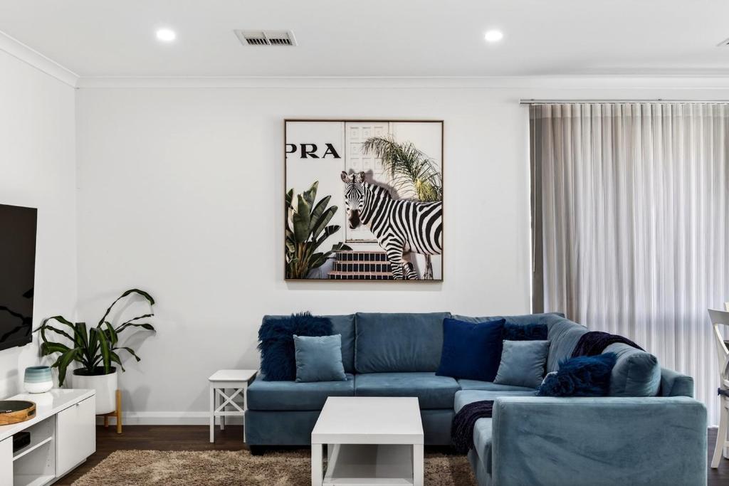 a living room with a blue couch and a zebra picture at DEAR8 - Madeley Retreat in Perth