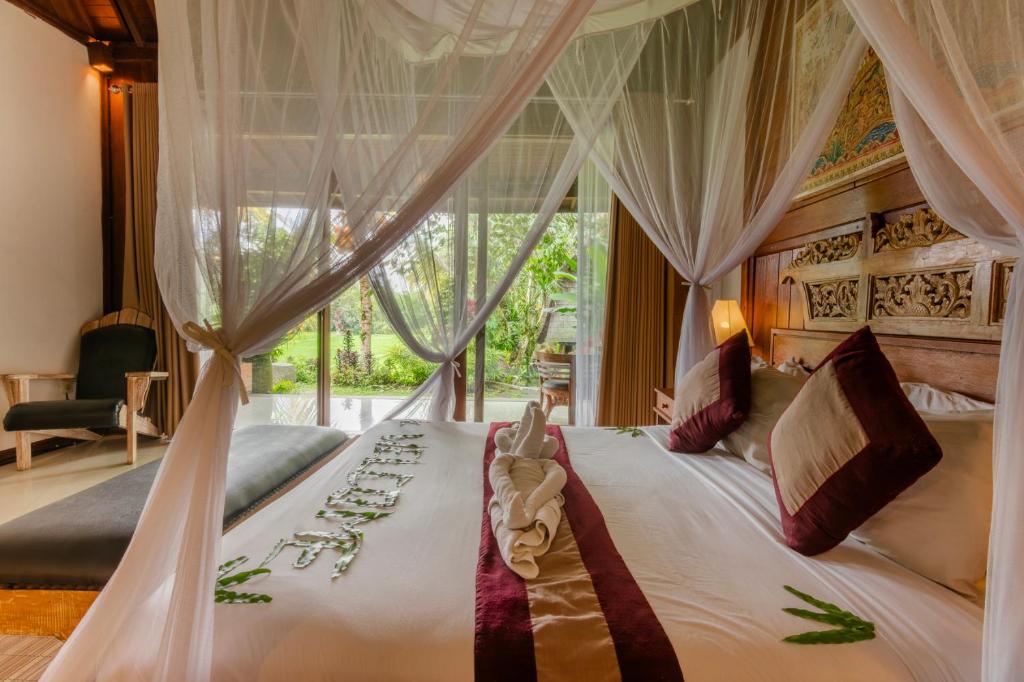 a bedroom with a large bed with a canopy at Dukuh Sebatu Villa Ubud in Tampaksiring