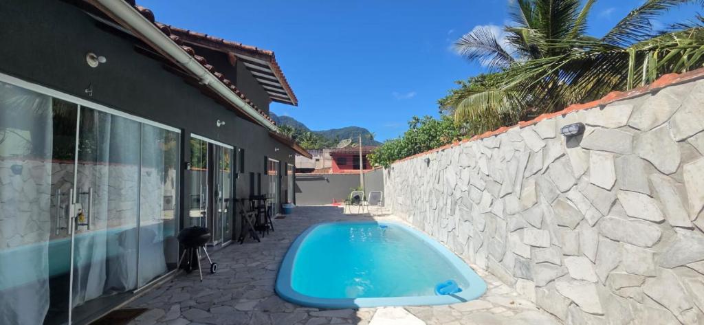 a swimming pool sitting next to a stone wall at Arandu chalés maresias in São Sebastião