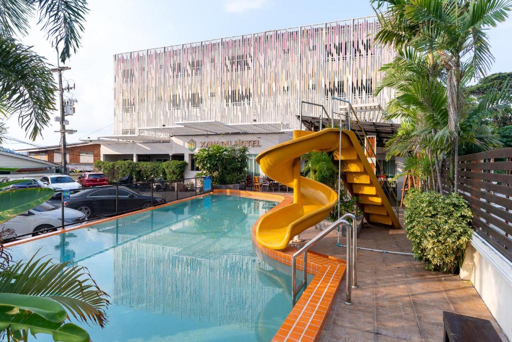 a swimming pool with a yellow slide in a building at Xanadu Hotel Utapao in Rayong