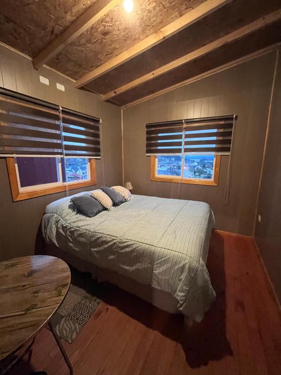 a bedroom with a large bed and two windows at Casa alojamiento Peumallen in Puerto Varas