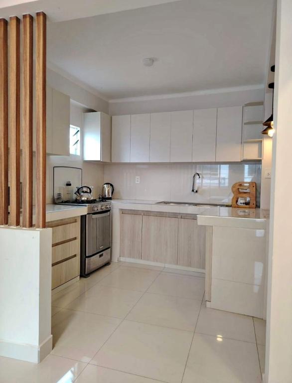 a large kitchen with white cabinets and appliances at La posada apartment in Cusco