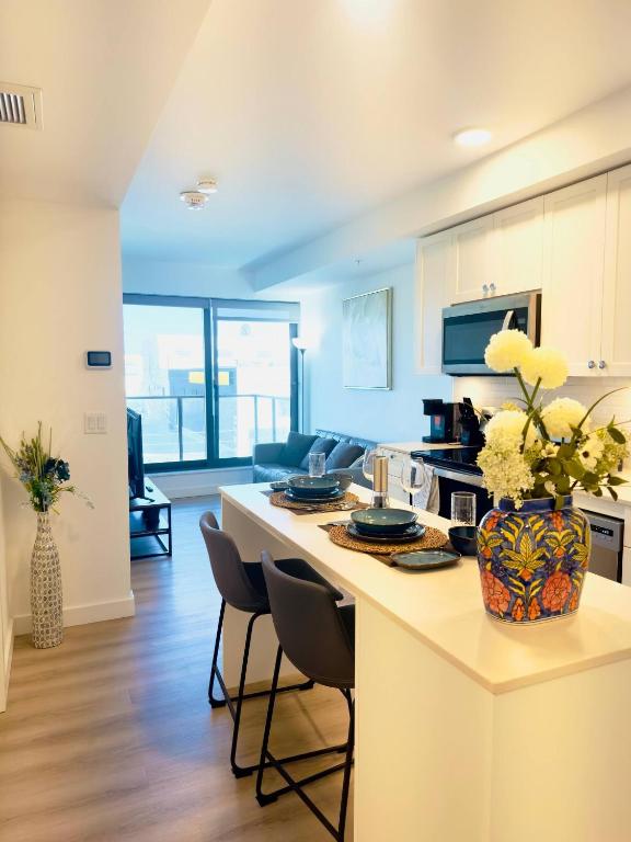 a kitchen with a counter with chairs and a table at Downtown Condo, Stylish Comfy in Calgary