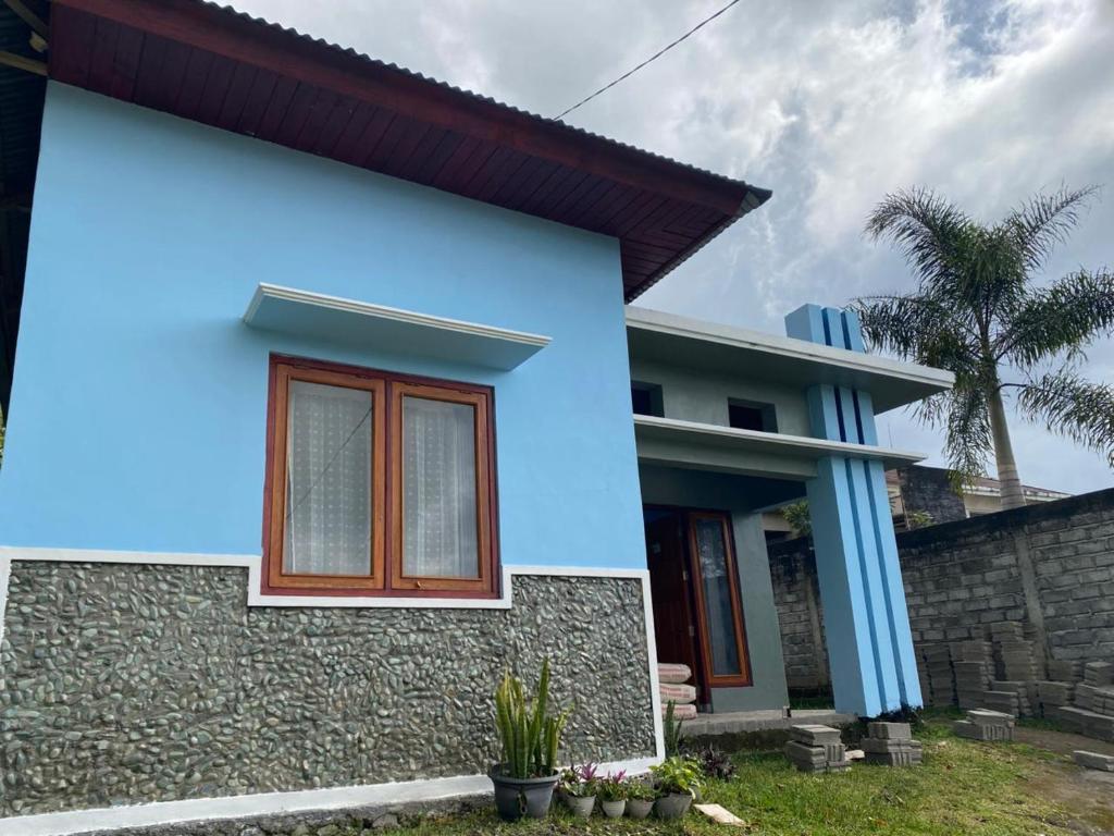a blue and white house with a palm tree at LovKend in Ruteng