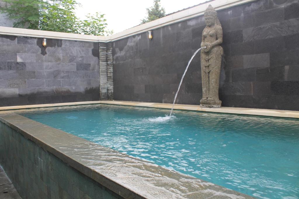 a fountain with a statue in a swimming pool at Dewi Antara Homestay in Ubud