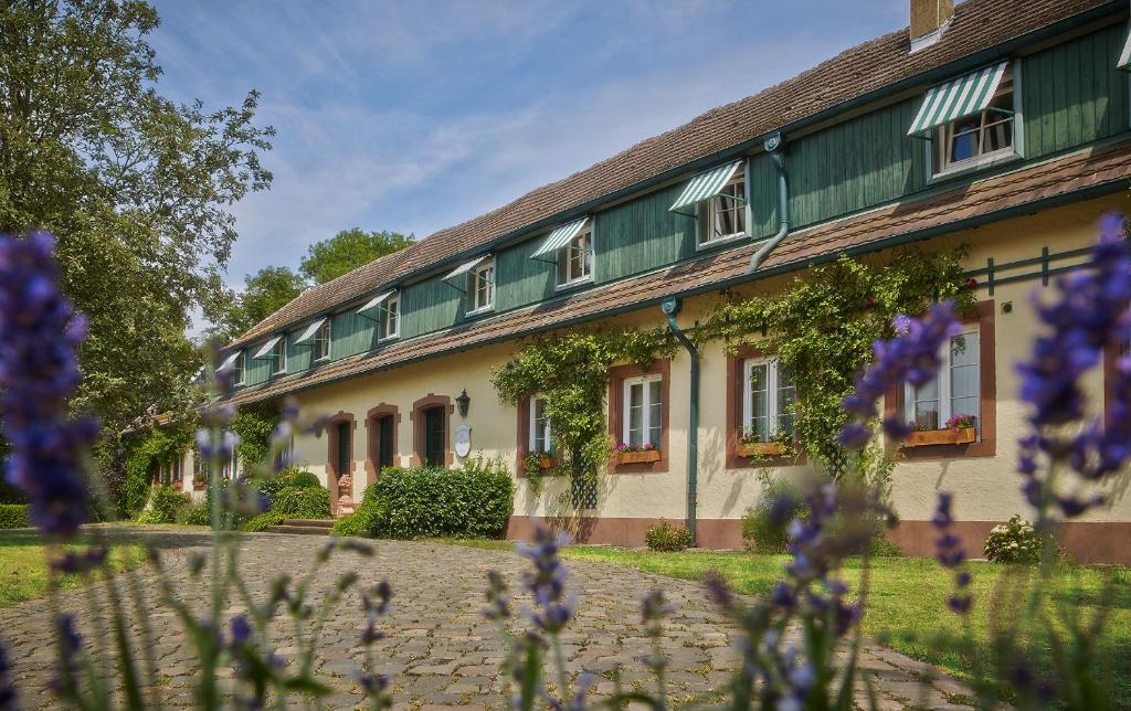 un bâtiment avec des fleurs violettes devant lui dans l'établissement Der Linslerhof - Hotel, Restaurant, Events & Natur, à Überherrn