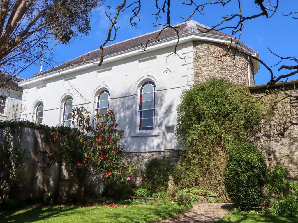 an old stone house with red flowers in front of it at The Music Room in Aveton Gifford