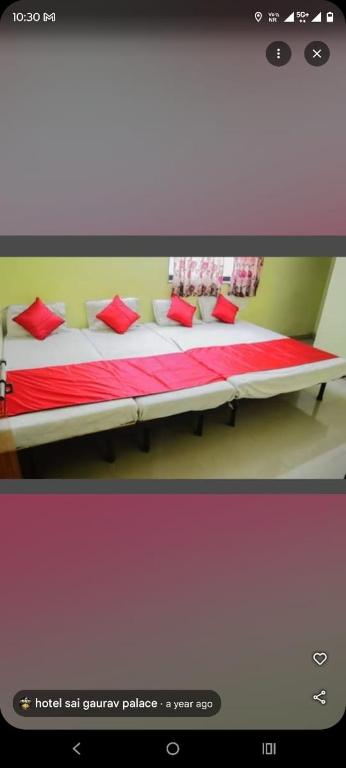 a bedroom with a bed with red pillows on it at Sai Gaurav Palace in Shirdi