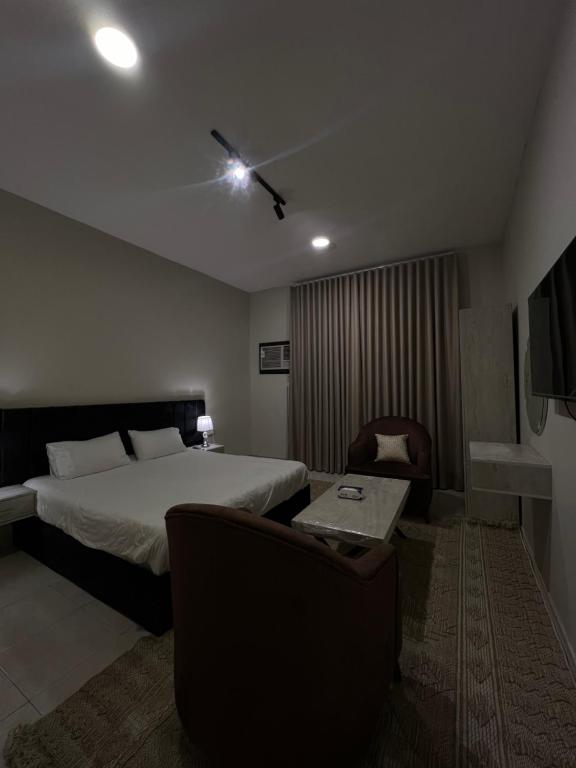 a bedroom with a bed and a couch and a tv at ملاذ للشقق المفروشة 2 in Tabuk
