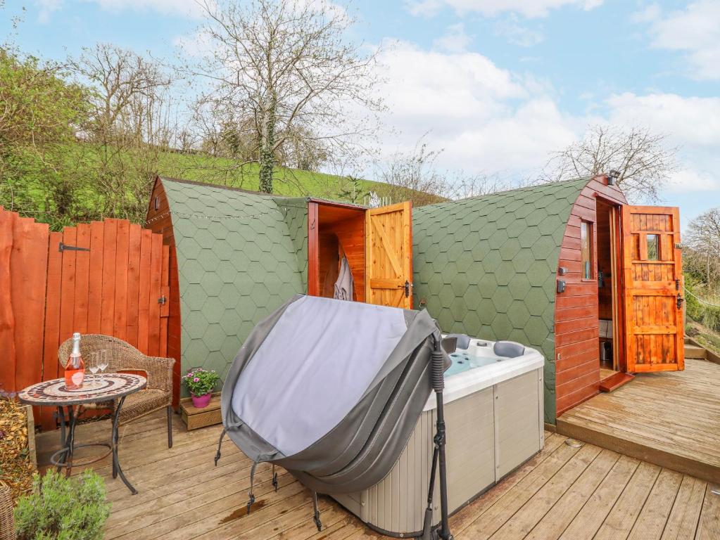 a small green building with a tub on a deck at The Rhiw in Newtown