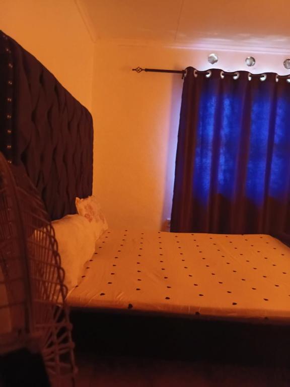 a bedroom with a bed with a blue curtain at Honeymoon villa Diani in Diani Beach