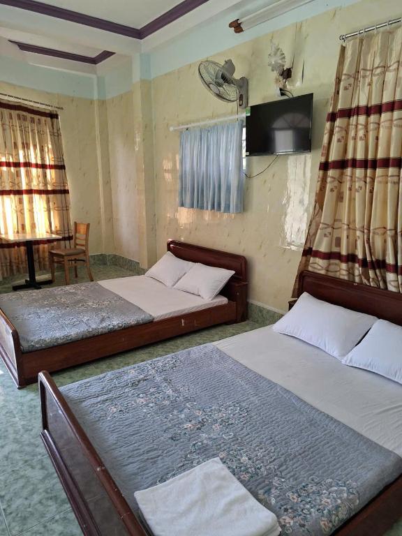 a bedroom with two beds and a television in it at Homestay Hồng Hoa in Hà Tiên