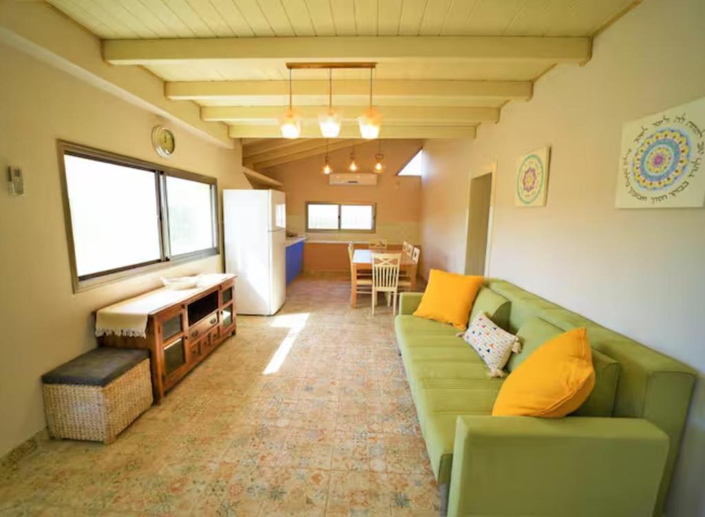 a living room with a green couch and a table at נוף הרים בר יוחאי - בית נופש מדהים עם בריכה וג'קוזי in Bar Yohai