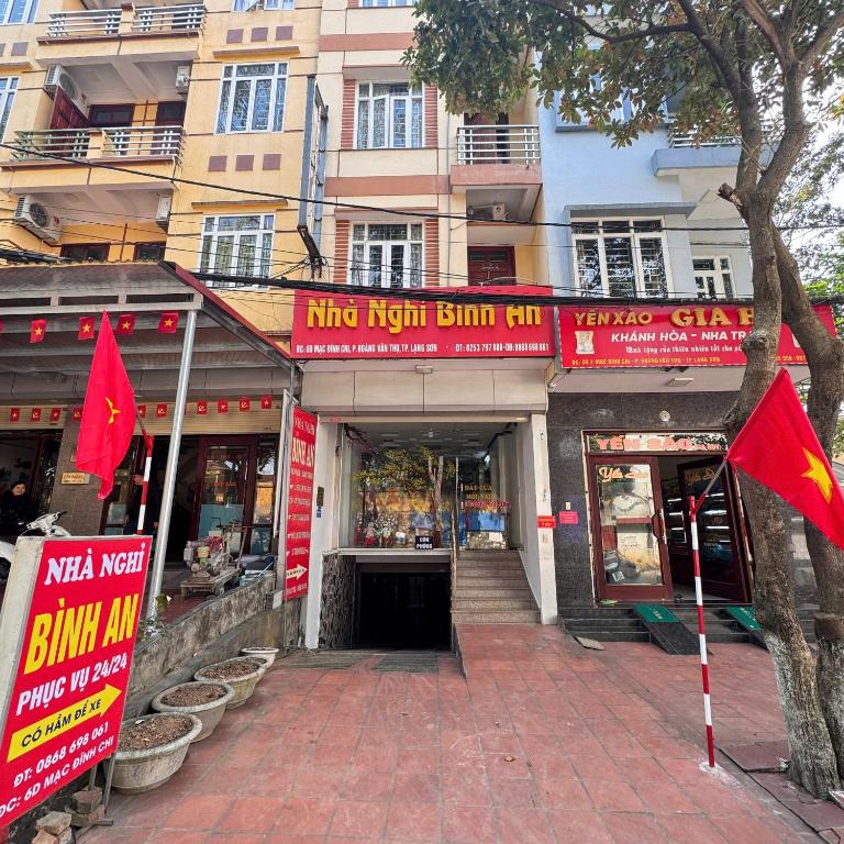 a building with red signs in front of a building at Nhà Nghỉ Bình An in Kỳ Lừa