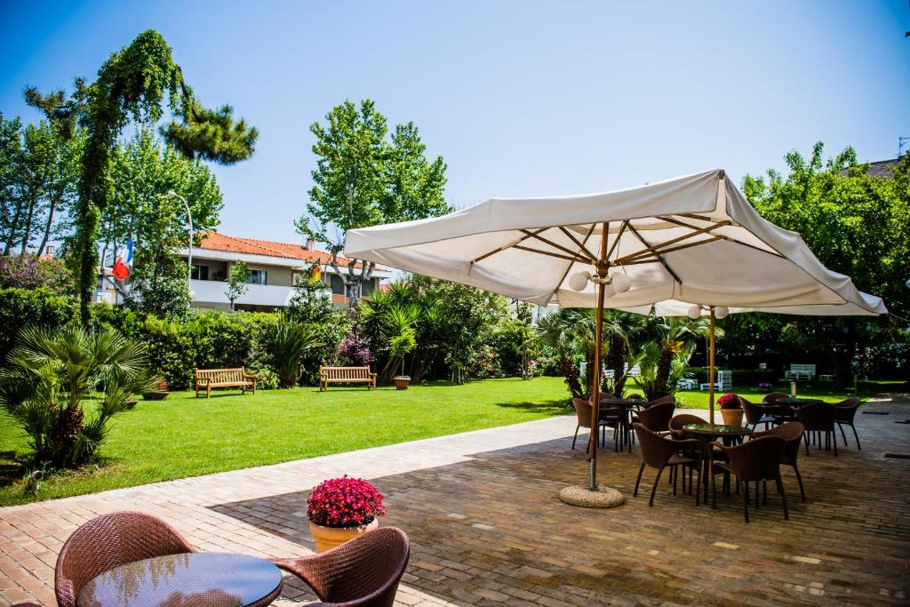 a patio area with a table, chairs, and umbrella at Phi Hotel Alcione in Francavilla al Mare