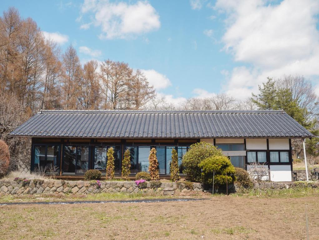 a house with a black roof in a field at ノキシタ in Hokuto