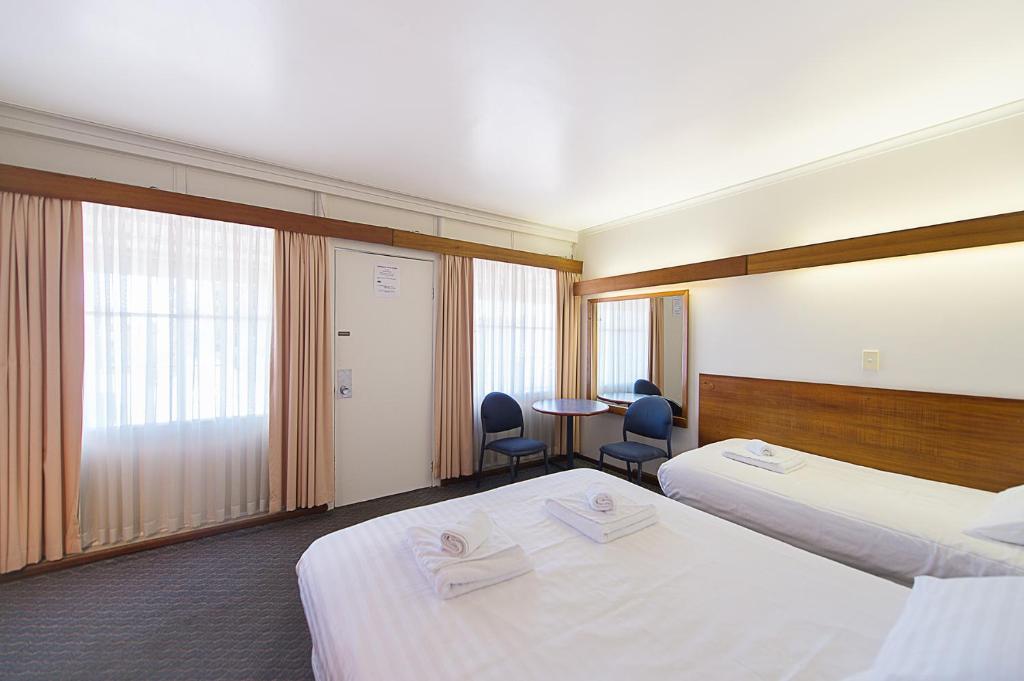 una camera d'albergo con due letti e un tavolo con sedie di Blue Hills Motel a Hobart