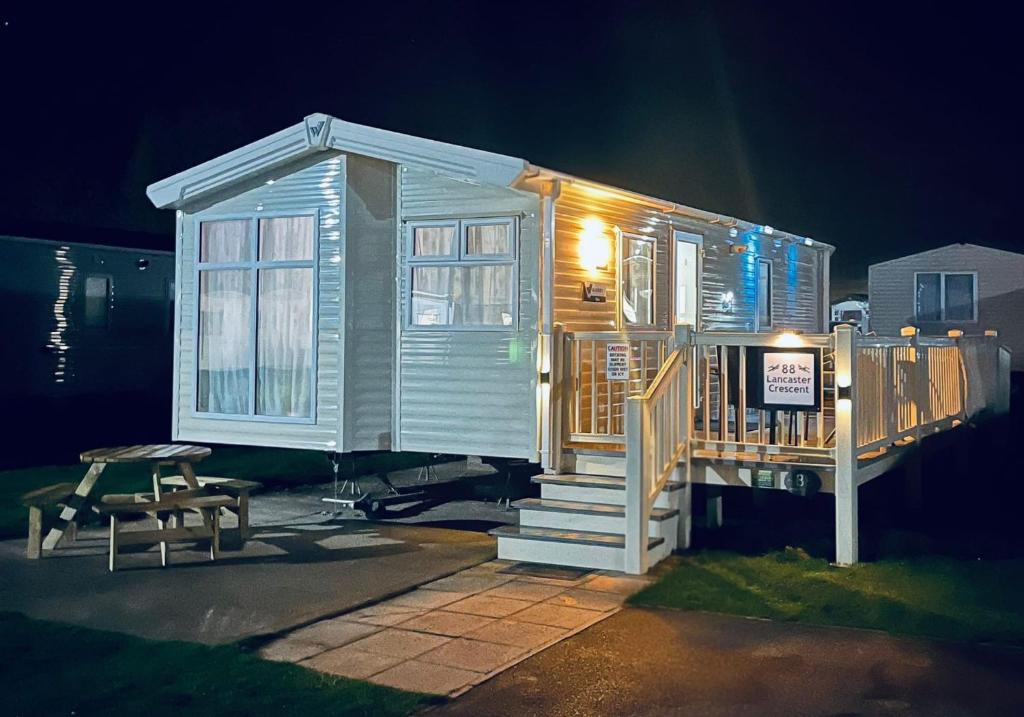 a tiny house with a porch and a table at Calypso Hot Tub Breaks Tattershall Lakes Pet Friendly in Tattershall