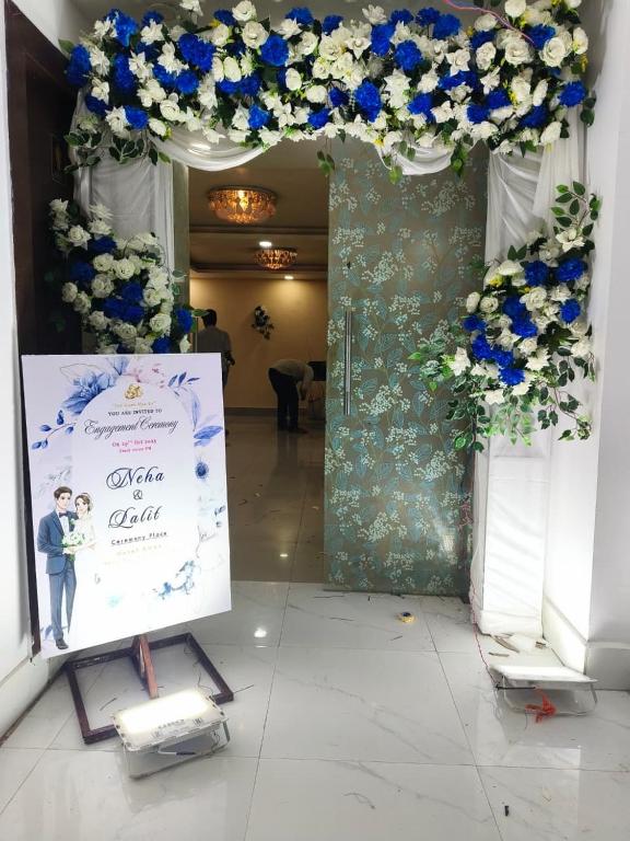 a wedding arch with blue and white flowers and a sign at Hotel Aman in Patna