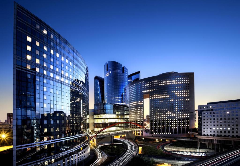 a city skyline with tall buildings and traffic at night at Moderne Apartement La Defense Paris in Courbevoie