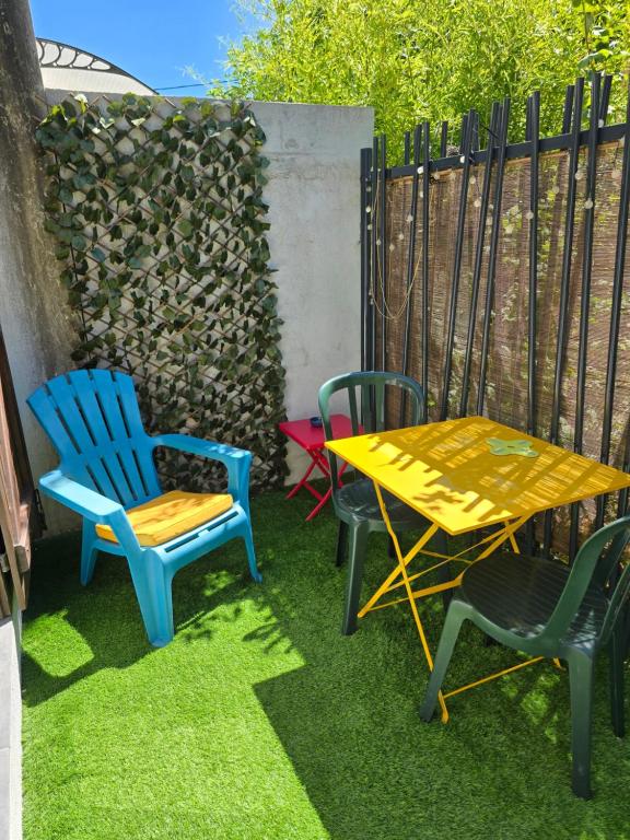 three chairs and a yellow table and chairs on the grass at Studette avec terrasse privée in Saint-Raphaël