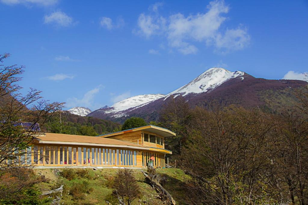 une maison sur une colline avec une montagne enneigée dans l'établissement Errante Ecolodge, à Puerto Williams