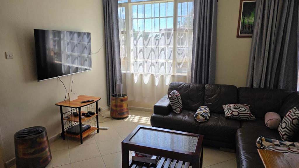 a living room with a leather couch and a television at Mambo Number Five in Entebbe