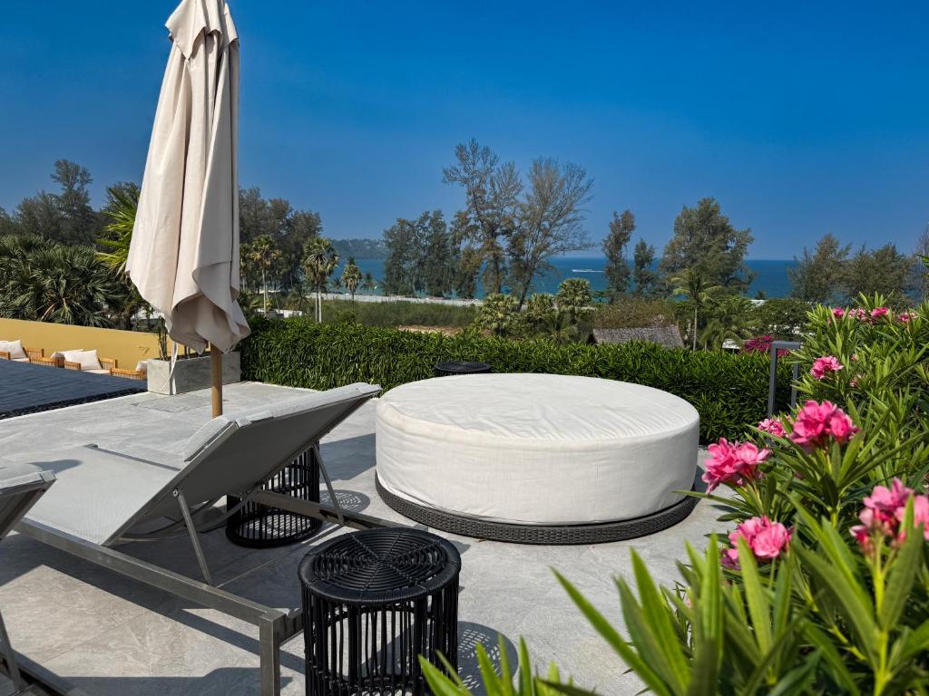 a patio with a table and an umbrella and flowers at Laguna Seaside 3 bed #84195 in Bang Tao Beach