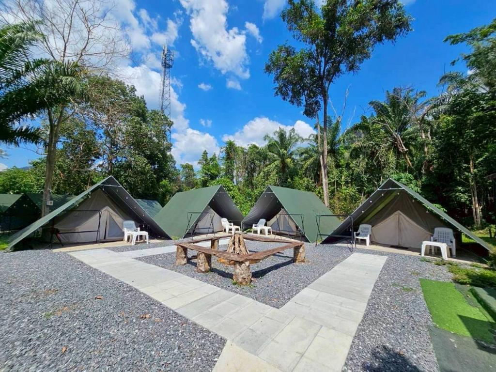 a picnic table in front of a group of tents at Nahm Khao Sok Hostel and Camping in Khao Sok National Park
