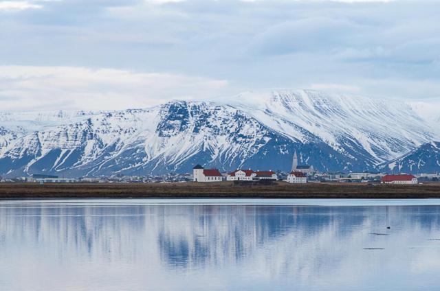a snow covered mountain in front of a body of water at RVK HoriZon in Álftanes