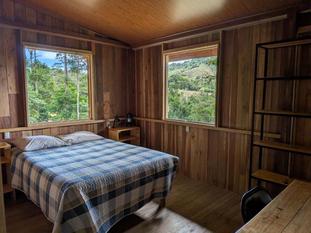 a bedroom with a bed and two windows at Rancho Ecojoya Paradise Mountain working farm in nature in San Isidro de El General