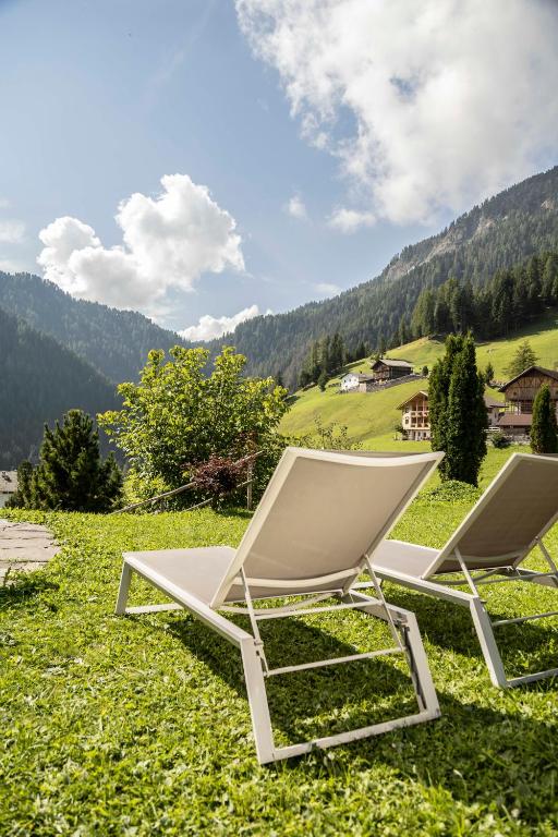 two white lounge chairs sitting on a field of grass at Arbea Apartments in Ortisei