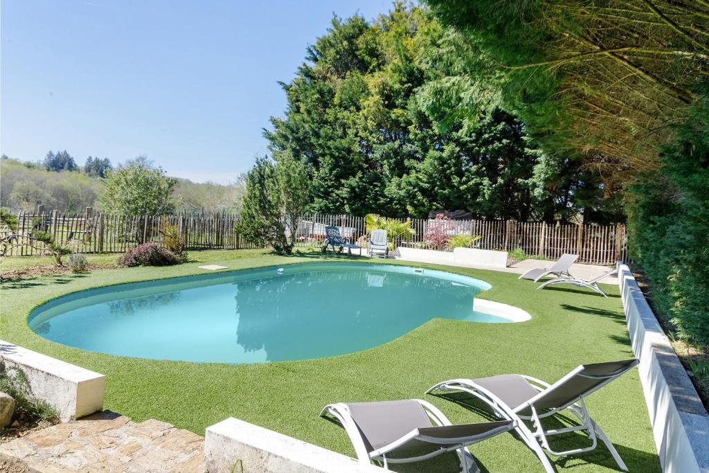 a swimming pool with lawn chairs and a fence at Le Ranch Des Ours in Champsac