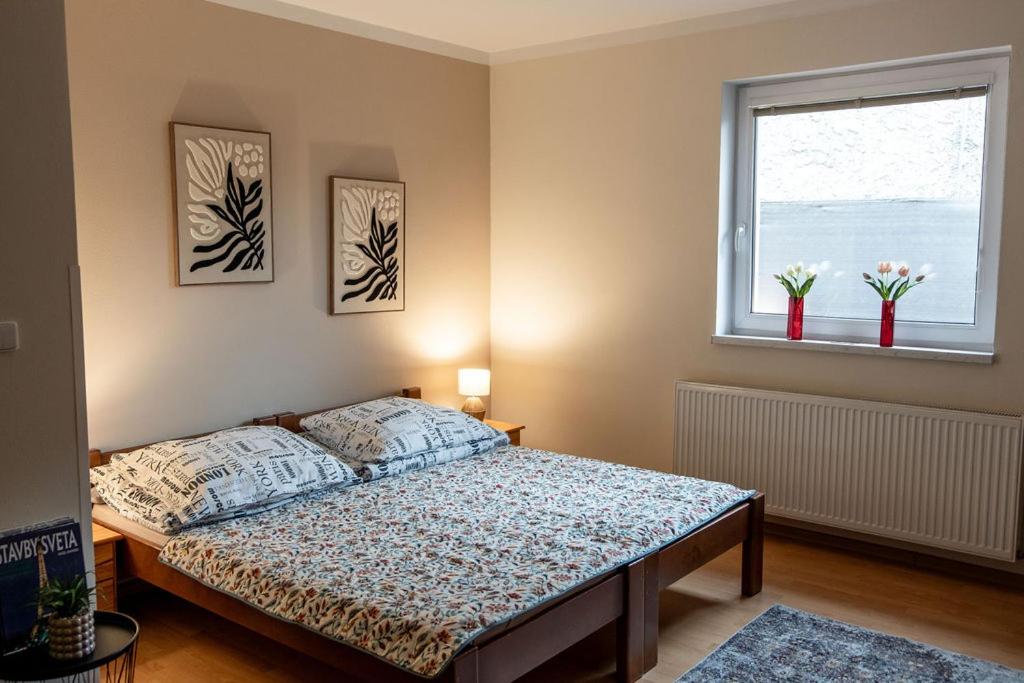 a bedroom with a bed and a window with flowers at Apartment Sučany in Sučany