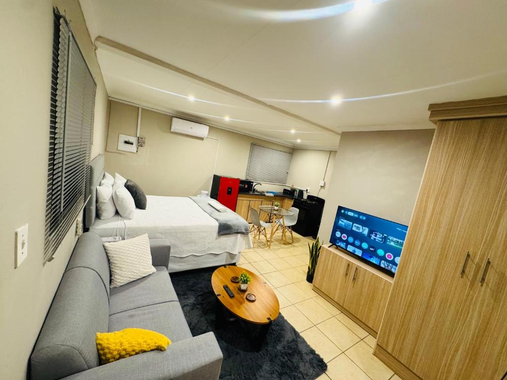 a room with a bed and a couch and a tv at Hei Stays Bachelor Apartment in Bronkhorstspruit